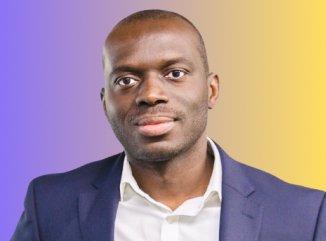 Portrait of a man wearing a white shirt and navy blazer with a gradient purple to yellow background.