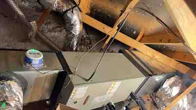 HVAC technician in a clean uniform inspecting a dusty evaporator coil inside a home attic - when your ac cant keep up with