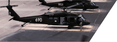 Two military helicopters on a landing pad