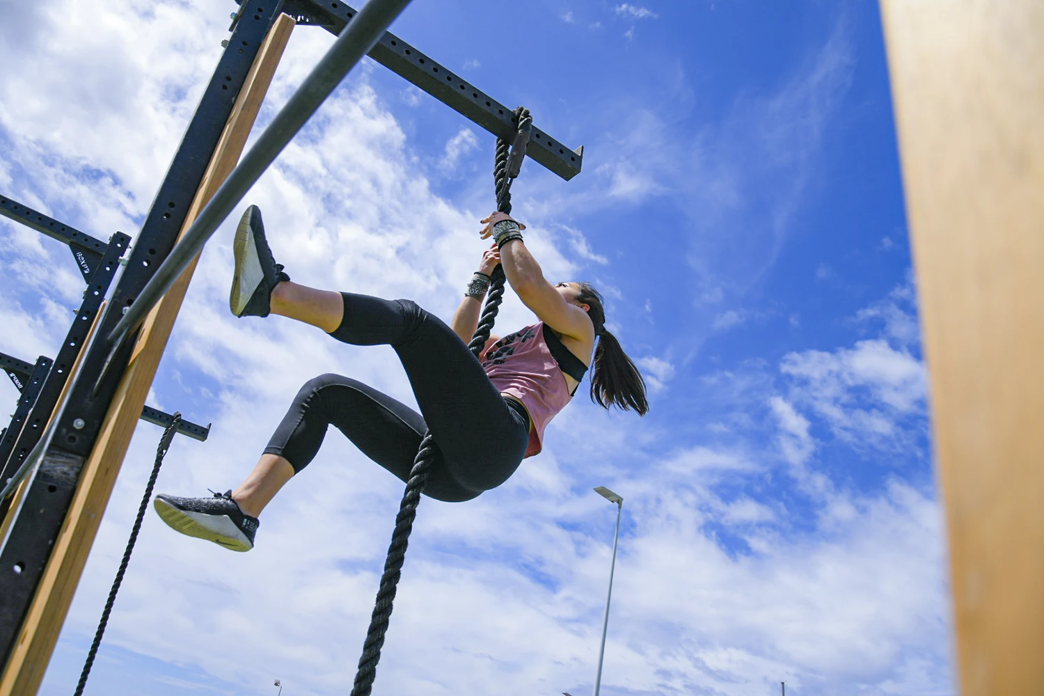 A woman climbing a rope, at Madeira Games CrossFit event.