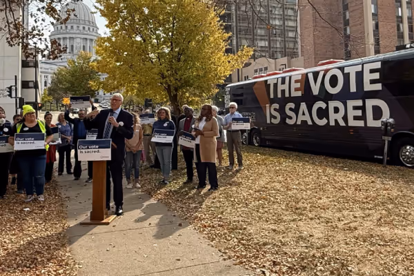 Rev. Paul Raushenbush speaking in front of a podium with the sign: "Our Vote is Sacred"