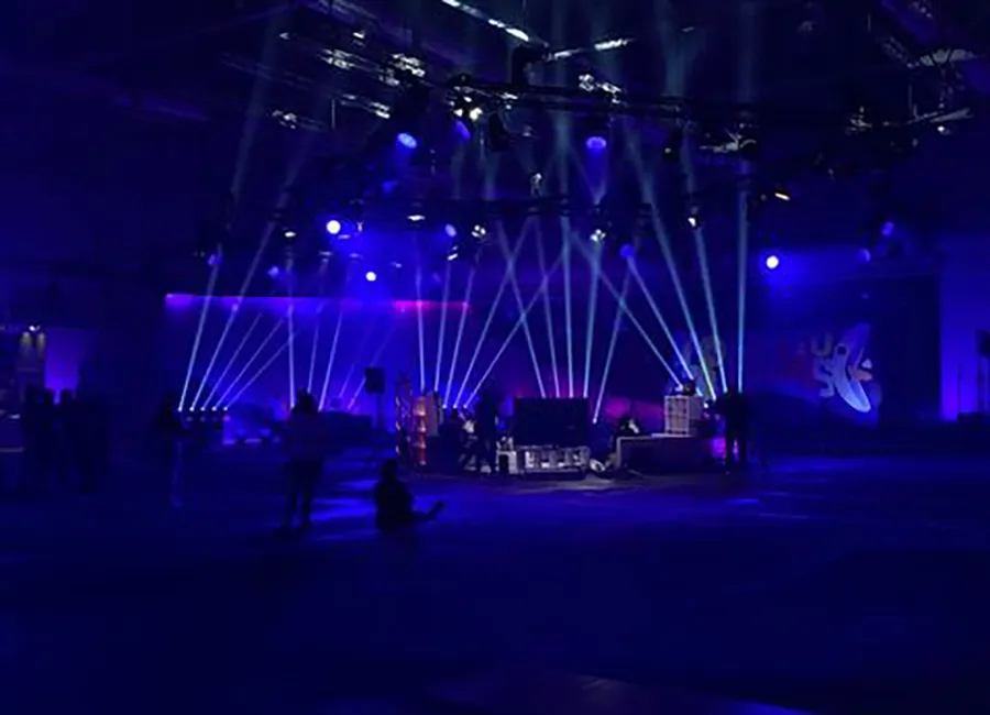 Ein Bblau illuminierter Raum mit weissen Lichtfächern, die in die Luft zeigen. in der Mitte Performt clueso