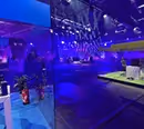 Ein Blau illuminierter Raum. vorne Links im Bild findet sich ein Glaskasten von dem aus ein Gamer seinen Livestream streamt und dahinter ein Großes Fernsehstudio welches blau ausgeleuchtet ist.