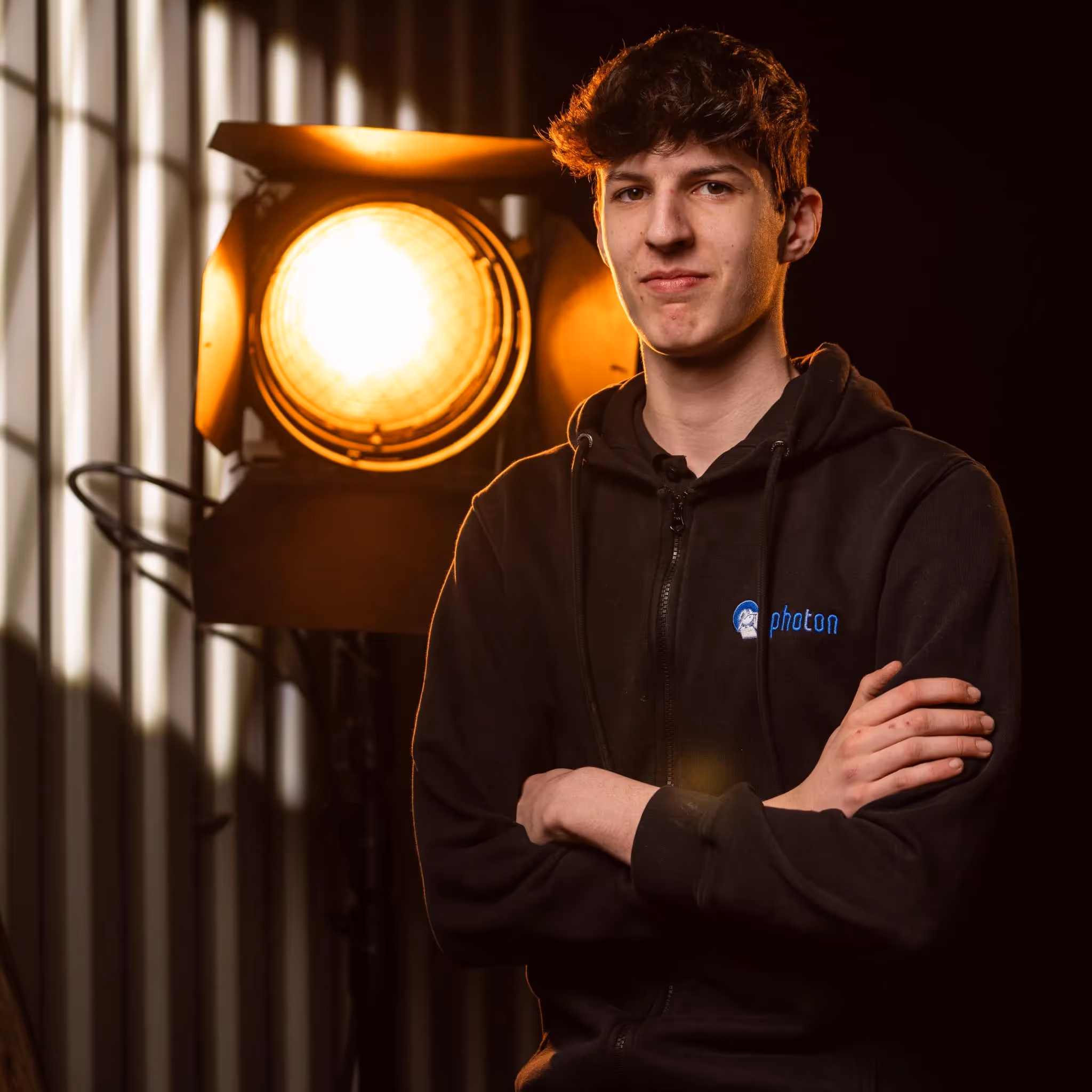 Oliver Odenthal mit Schwarzen Haaren und einem Schwarzen Pullover lächelt in die Kamera, eine Stufenlinse steht hinter ihm