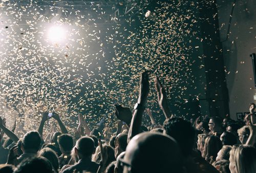 Eine Menschenmenge auf einem Konzert Jubelt. Konfetti wird abgefeuert