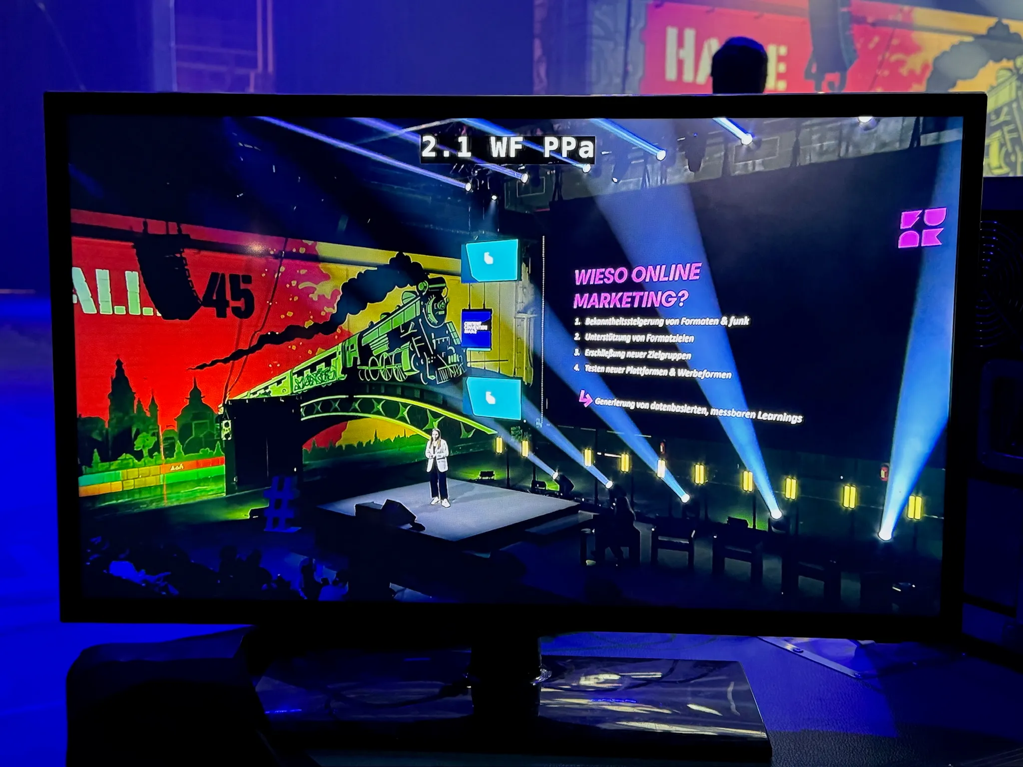 Es wird ein Monitor gezeigt auf dem ein Redner vor einer Led Wand steht und mit unserer Eventtechnik seine Präsentation hält