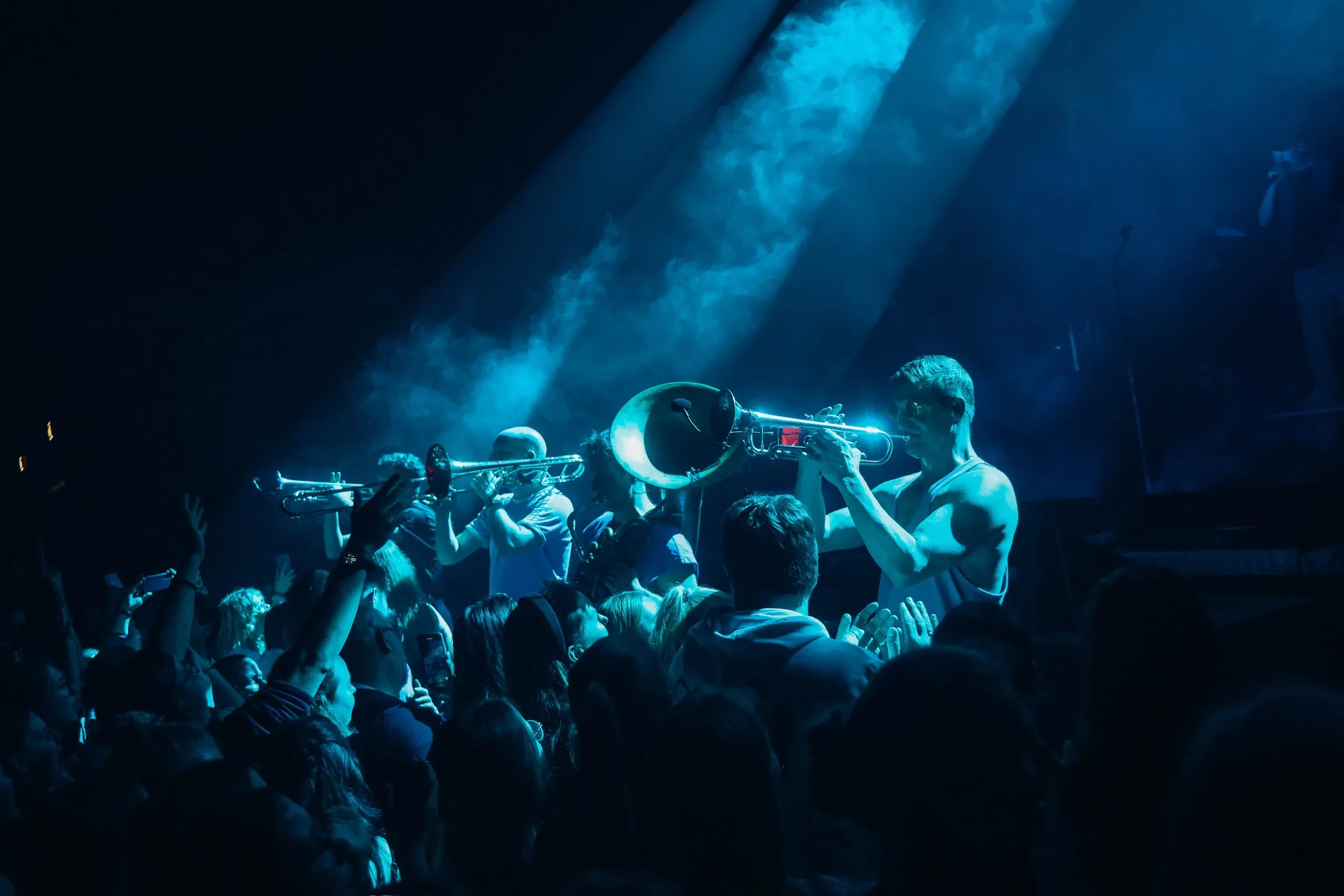 Eine Gruppe von Musikern steht in einer Rehei und wird von Hinten mit Movinglights angeleuchet