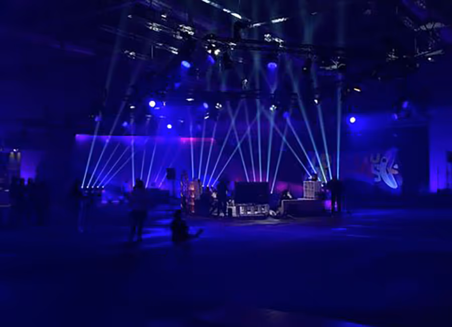 Ein Bblau illuminierter Raum mit weissen Lichtfächern, die in die Luft zeigen. in der Mitte Performt clueso