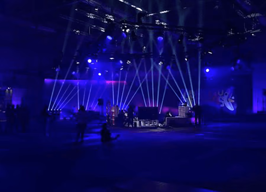 A blue-lit room with white light fans pointing upward while Clueso performs in the centre, by photon