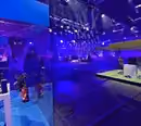 Ein Blau illuminierter Raum. vorne Links im Bild findet sich ein Glaskasten von dem aus ein Gamer seinen Livestream streamt und dahinter ein Großes Fernsehstudio welches blau ausgeleuchtet ist.