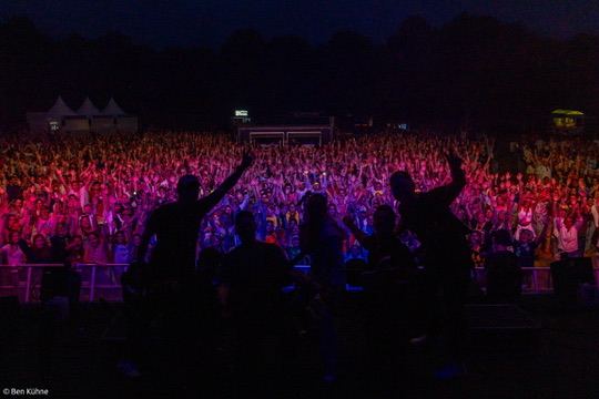 Blick von der Bühne auf rund 3.000 Feiernde in pink-blauem Festivallicht – BÜTZ & BEATS 2026 bei Nacht