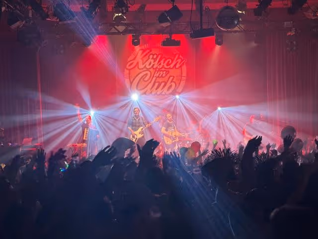 Band in colourful stage lighting in front of a cheering crowd – lighting and sound technology by photon