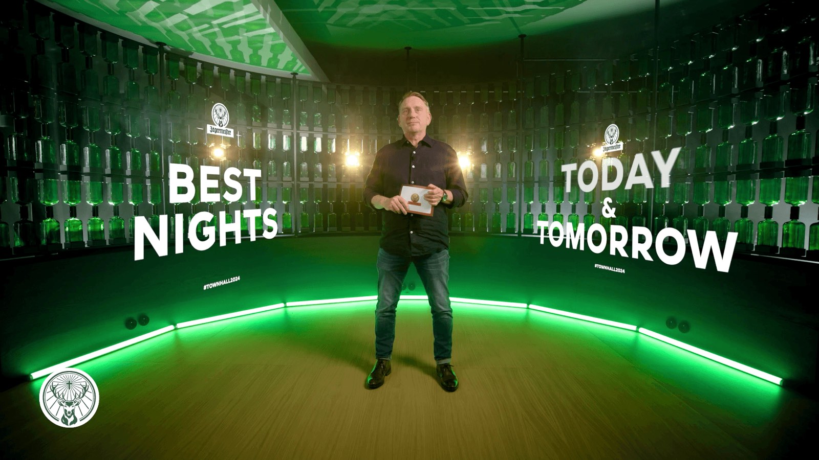 Presenter in the green-lit streaming studio set of the Jägermeister town hall – hybrid event production with technology by photon