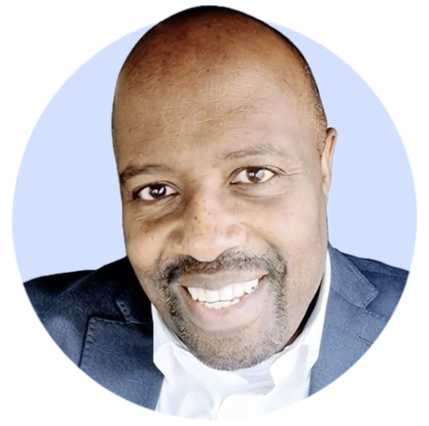 Smiling bald man with a short beard wearing a dark blazer and white shirt.