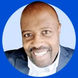 Smiling bald man with a short beard wearing a dark blazer and white shirt.