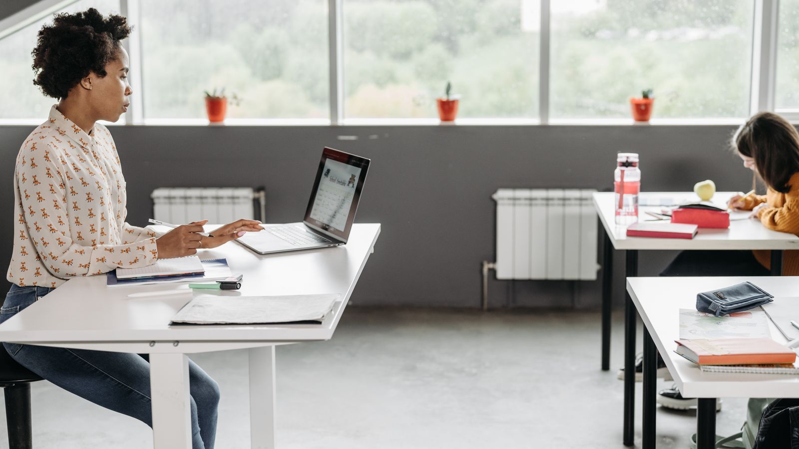 K-12 teacher reviewing email on a laptop at her classroom desk