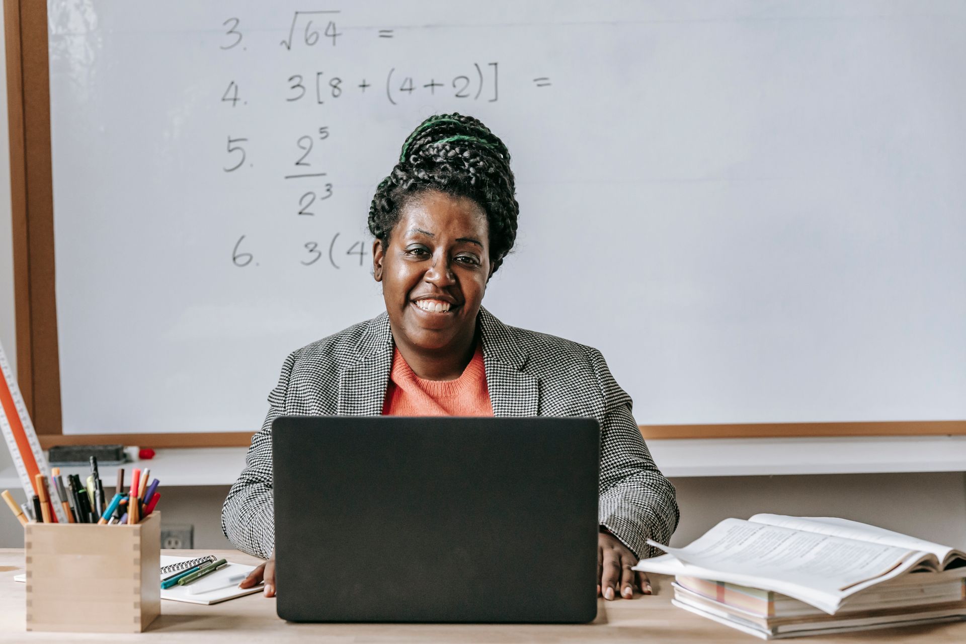 Smiling teacher using a laptop in a classroom