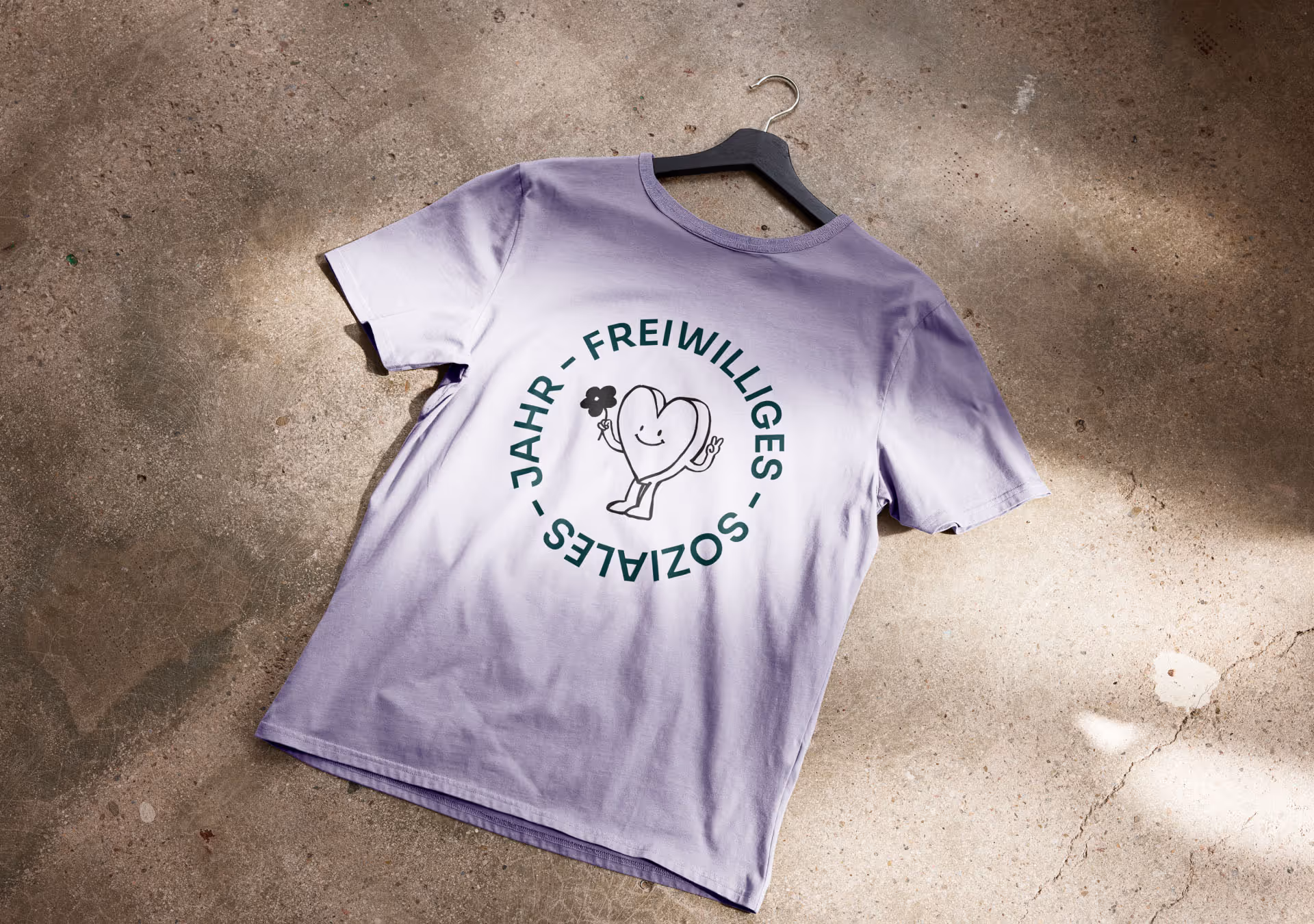 Lila T-Shirt mit rundem FSJ-Logo und Herzillustration als Teil der neuen Bekleidungslinie im Rahmen des FSJ-Re-Brandings, gestaltet von der Full-Service Agentur Achtzehn Grad.