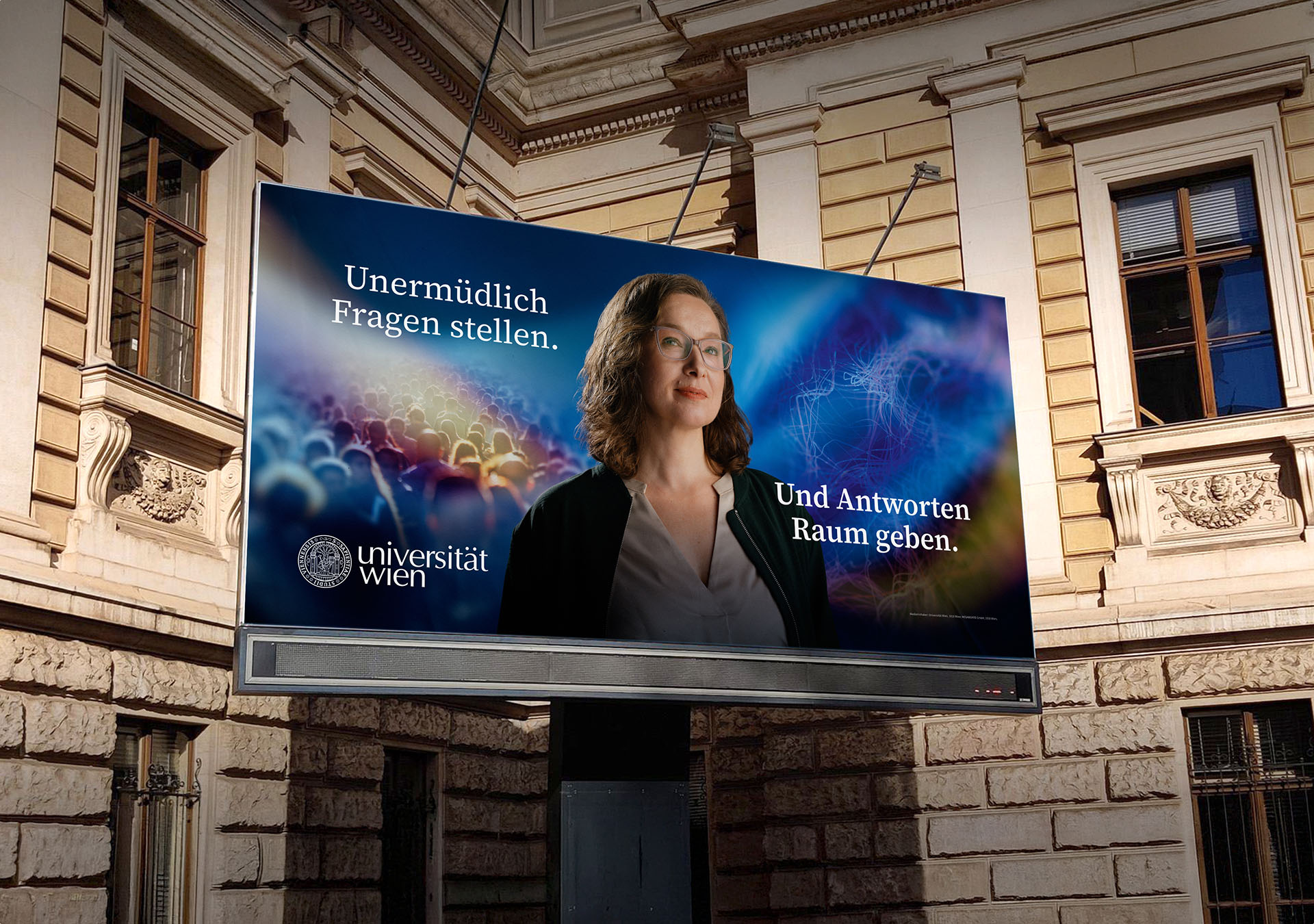 Werbetafel der Universität Wien mit Porträt einer Frau und der Aufschrift: Unermüdlich Fragen stellen.