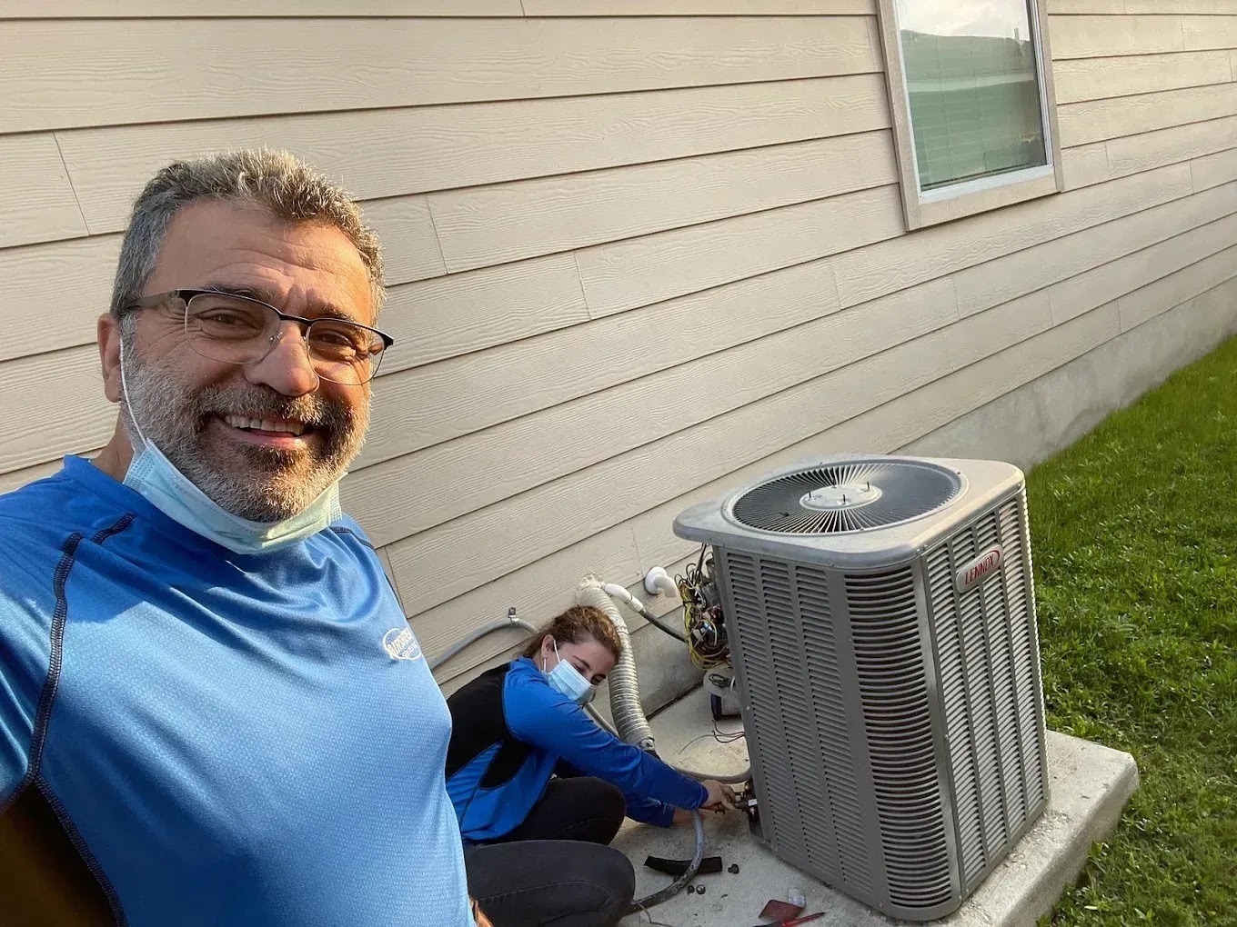 Technician inspecting an air conditioning unit during a comprehensive seasonal tune-up