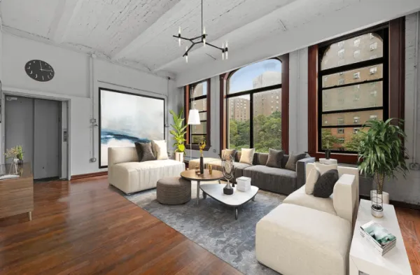Modern living room with large arched windows overlooking city buildings, beige sectional sofas, round coffee tables, and wooden flooring.