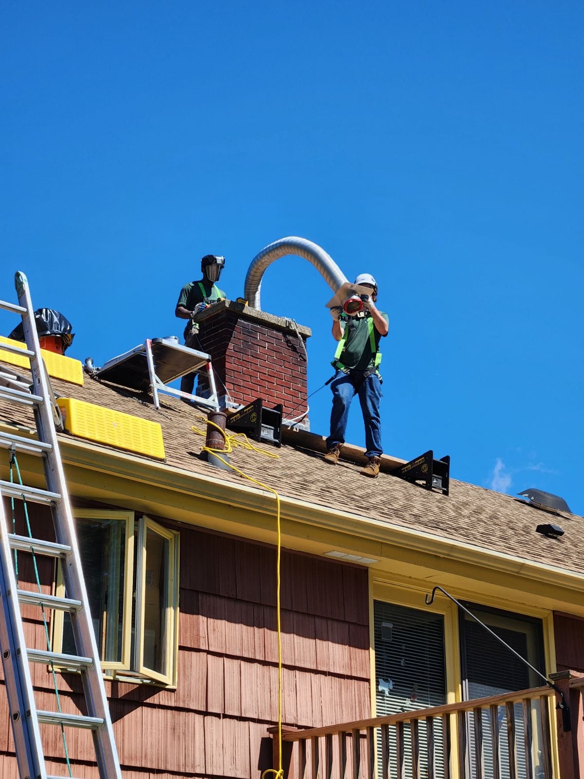 Dave's Chimney Service crew feeding a stainless steel liner into a brick chimney