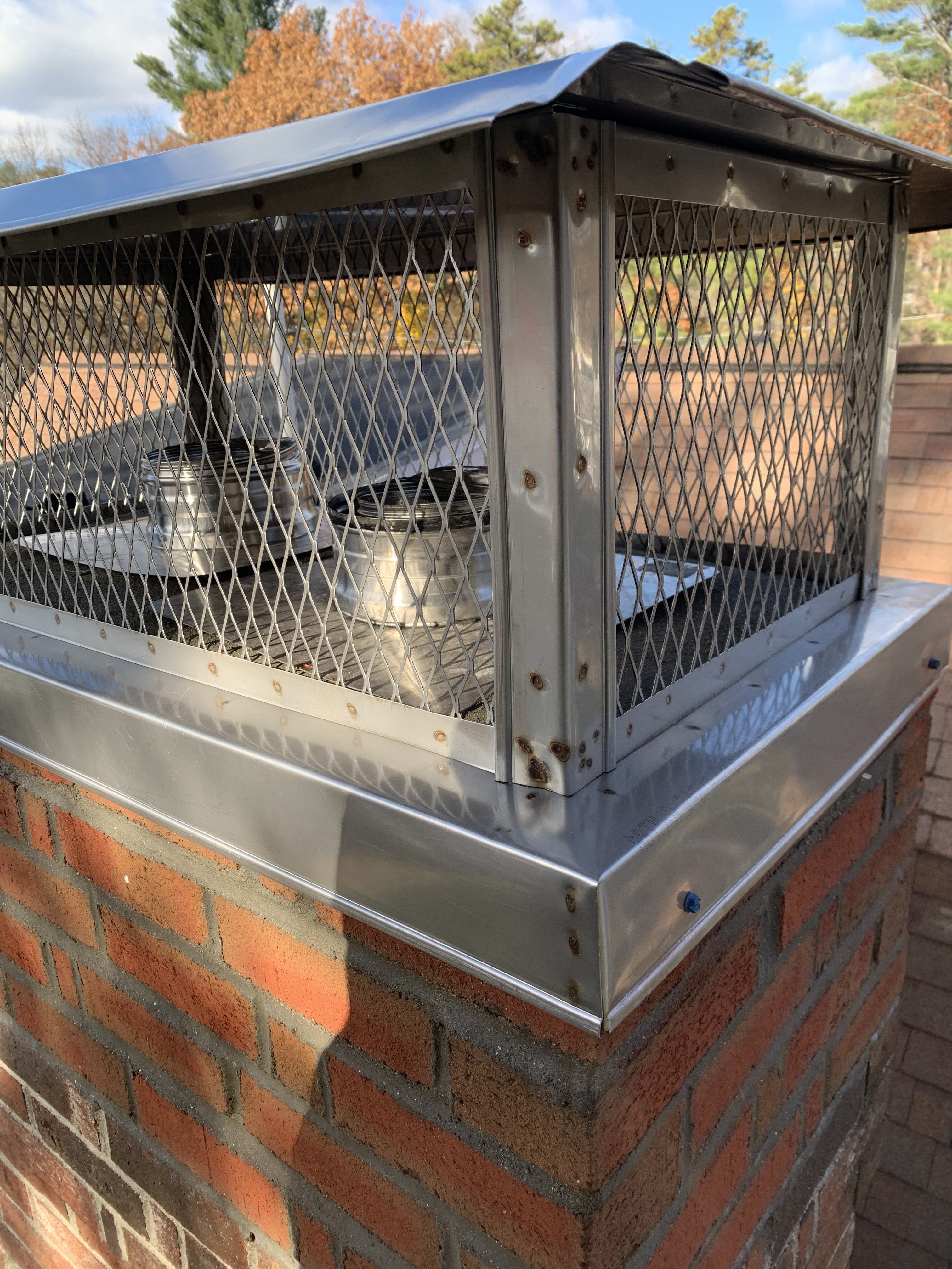 Stainless steel multi-flue chimney cap installed on a brick chimney