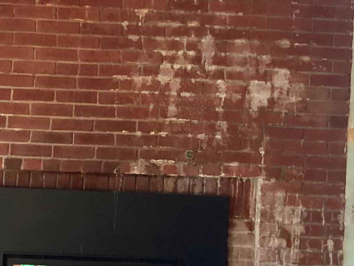 Water leak stains on interior chimney brick above a fireplace insert