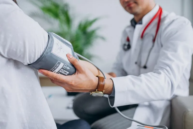 A doctor taking someone's blood pressure. Their face is not visible.