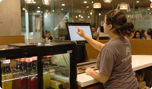 Empleado de restaurante usando una pantalla táctil de punto de venta en el mostrador