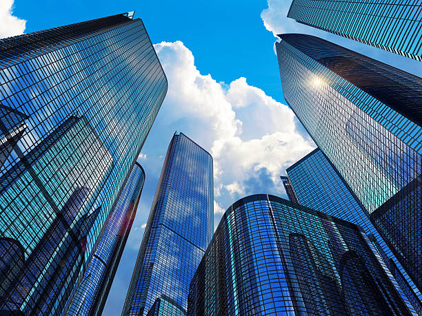 Glass-clad office towers seen from street level against a bright blue sky