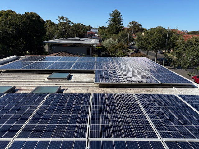 Rows of freshly cleaned solar panels spanning a flat suburban rooftop