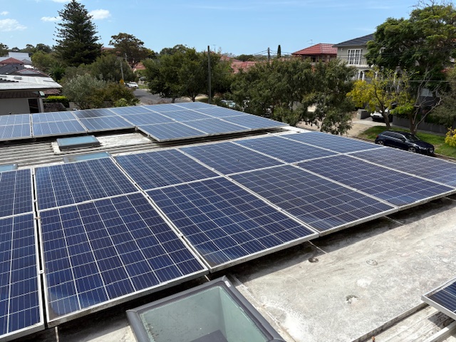 Large solar panel array beside a skylight on a flat suburban rooftop
