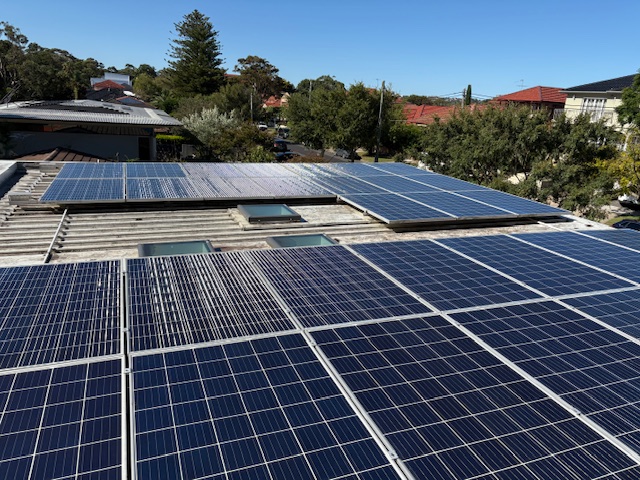 Clean rooftop solar array on a flat roof overlooking leafy suburban homes