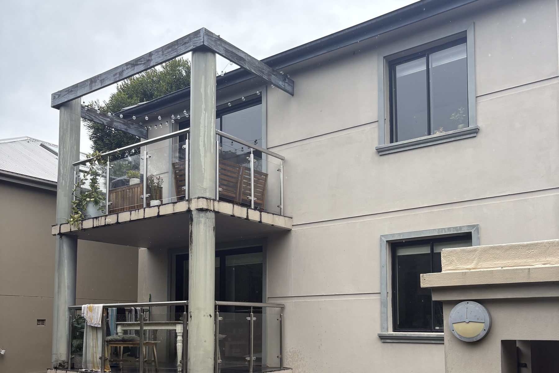 Rendered two-storey Sydney apartment building with glass balcony balustrade, cleaned by soft washing.