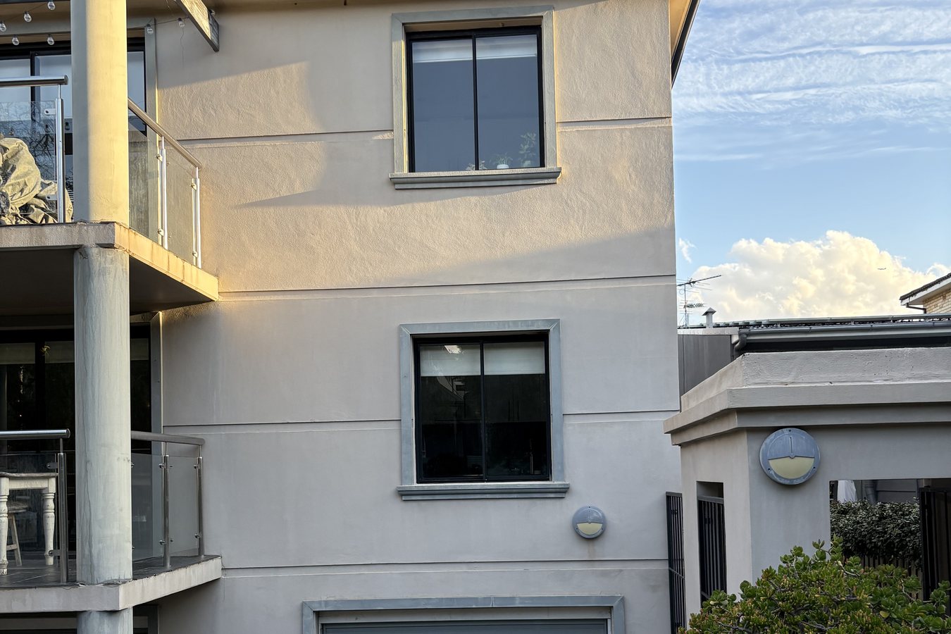 Rendered apartment facade with large windows and glass balustrades cleaned from the ground.