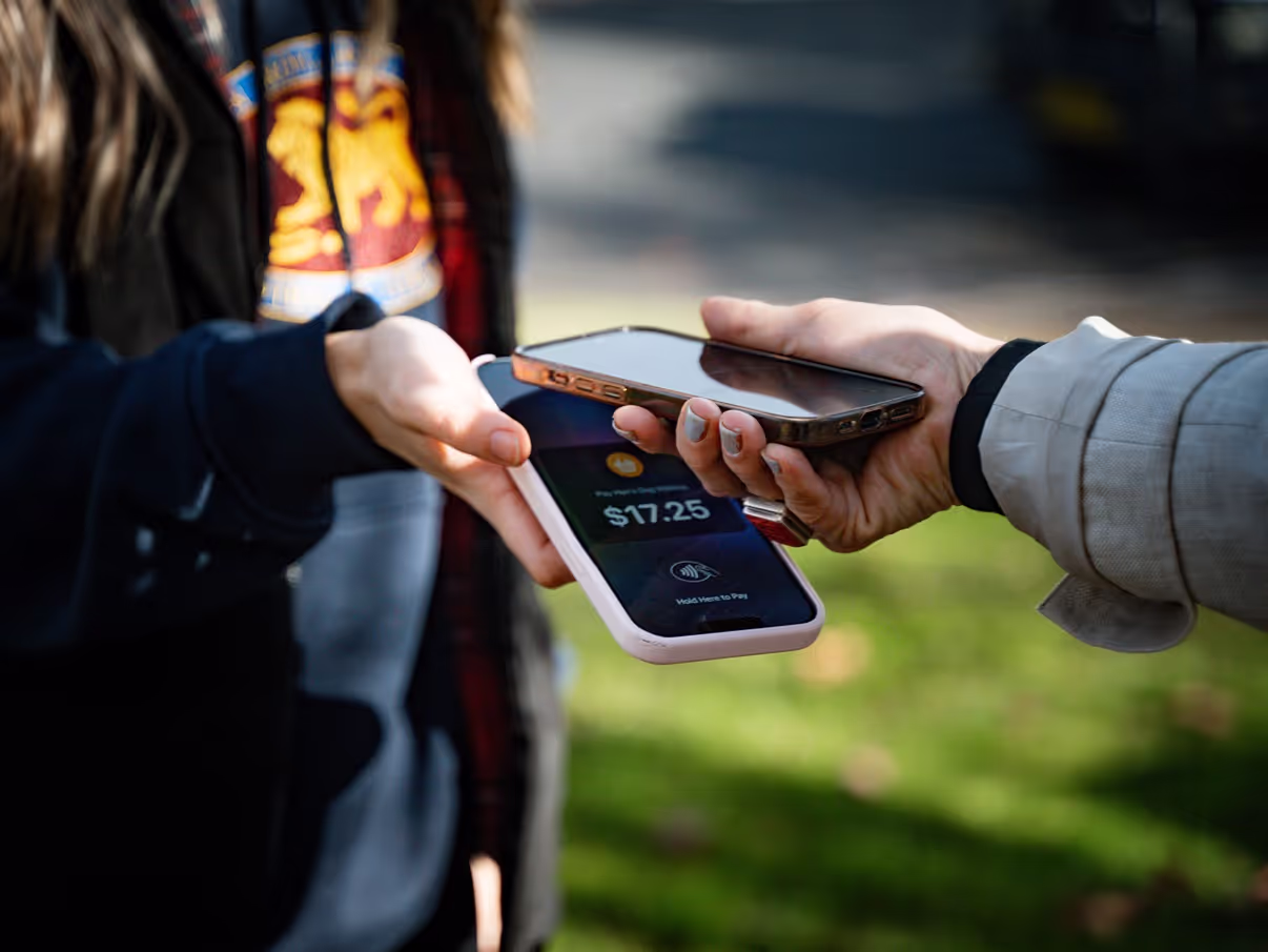 Two people completing a contactless payment using NFC technology on their mobile phones in an outdoor setting, demonstrating the ease and security of NFC transactions.