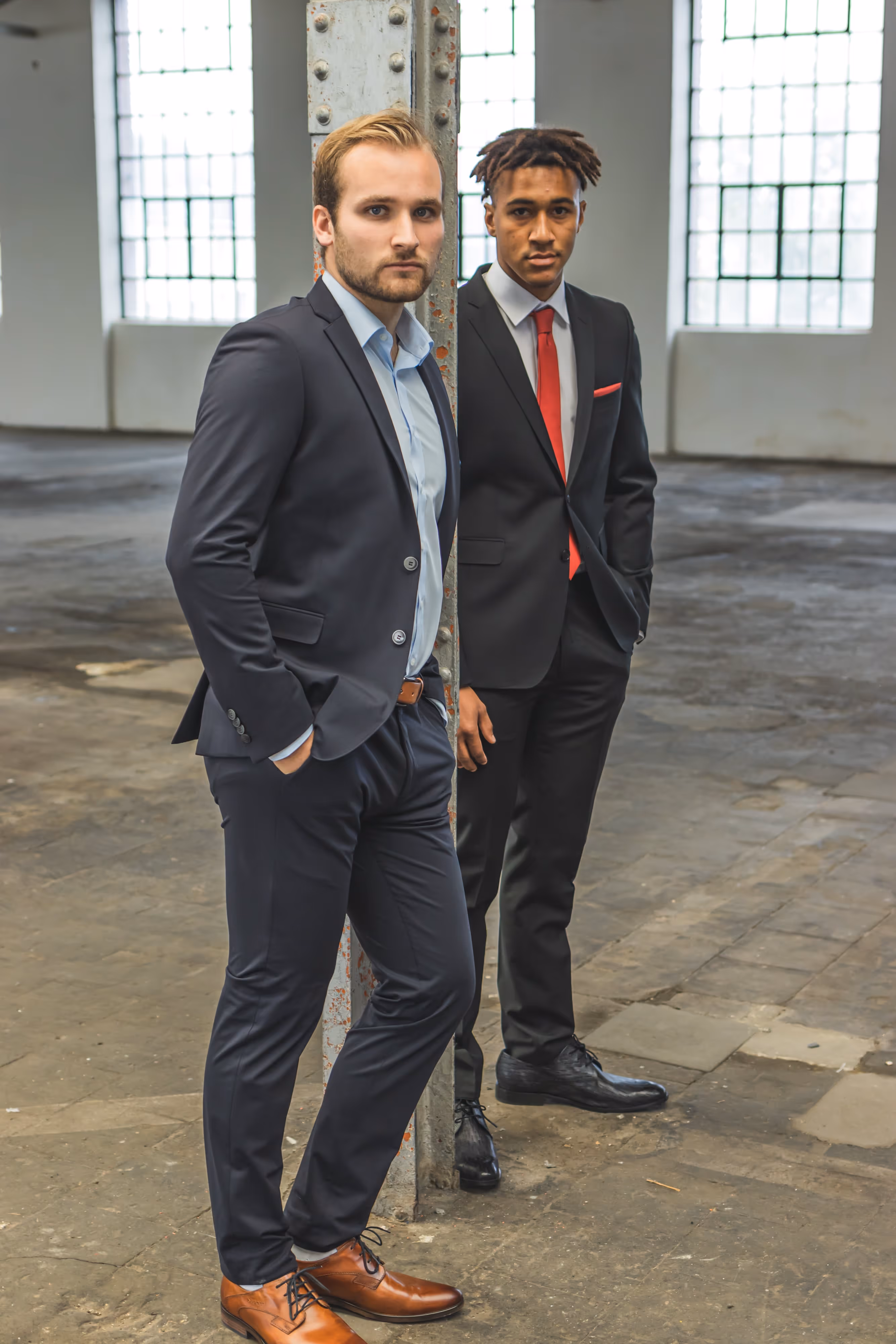 Zwei junge Männer stehen in einem Return-Herrenanzug in einer Fabrik.