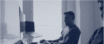Ein Mann sitzt am Schreibtisch und arbeitet an einem Computer in einem hellen Raum.