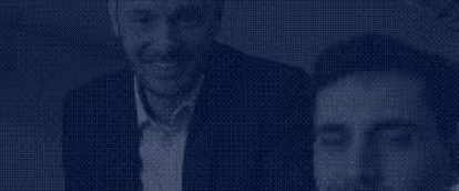 Zwei lächelnde Männer in formeller Kleidung, die sich nebeneinander befinden.