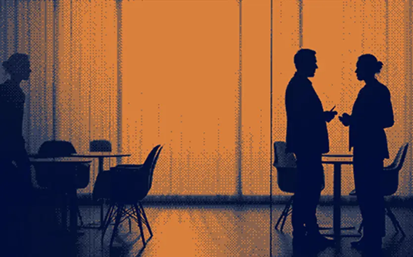 Silhouettes of three people in a room with tables and chairs in front of a large orange colored window, two of them having a conversation.