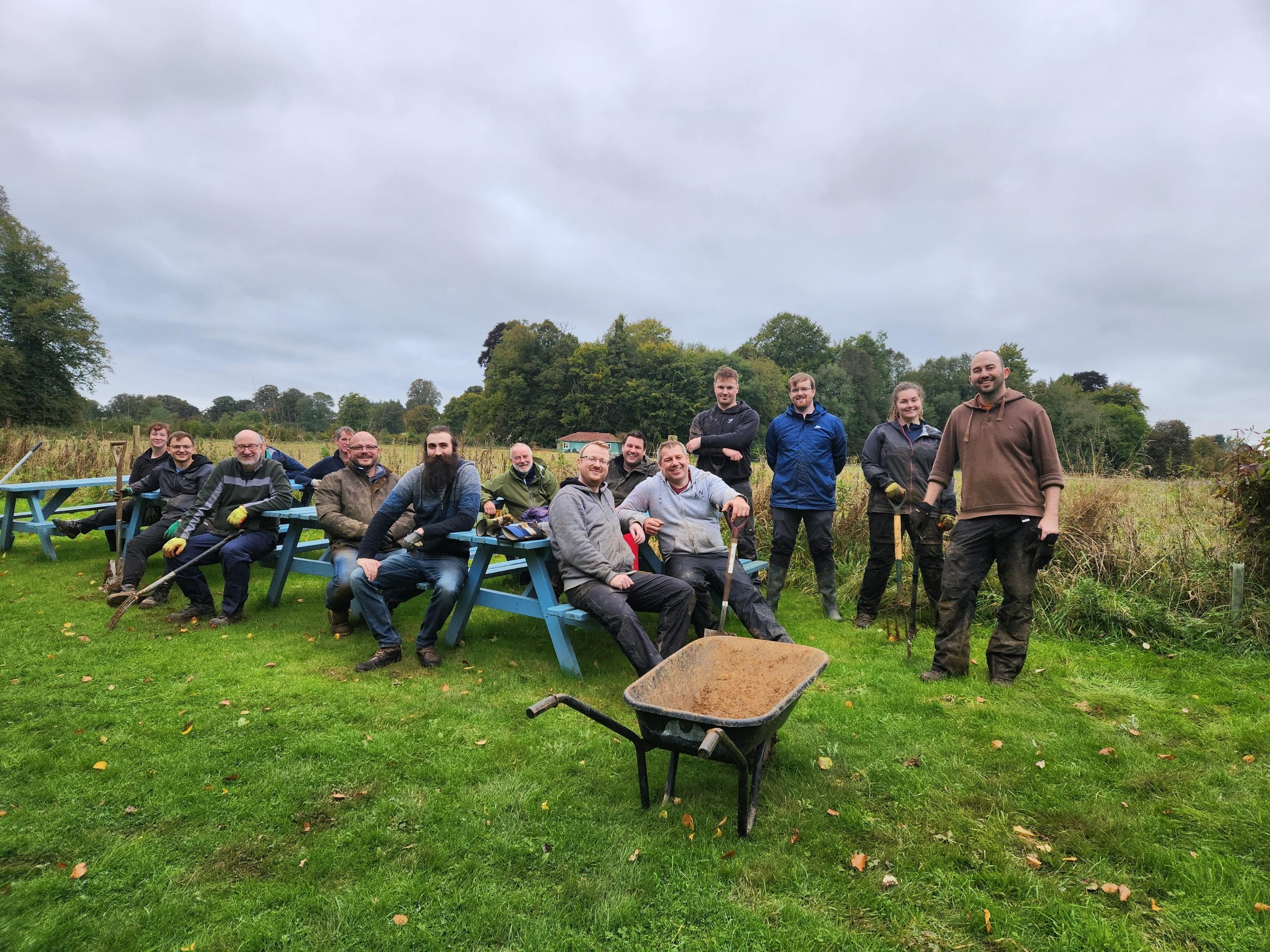 Group of HD employees sat on benches with gardening tools and a wheel barrow