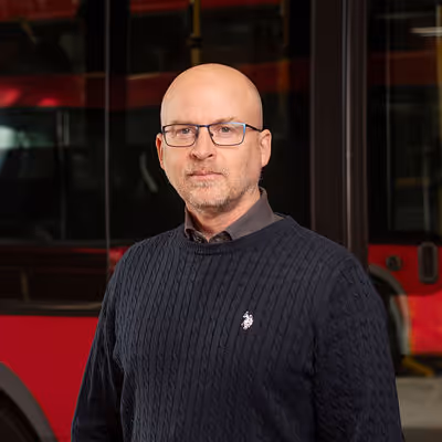 Bild på Ulf Nordin framför en röd LLT buss