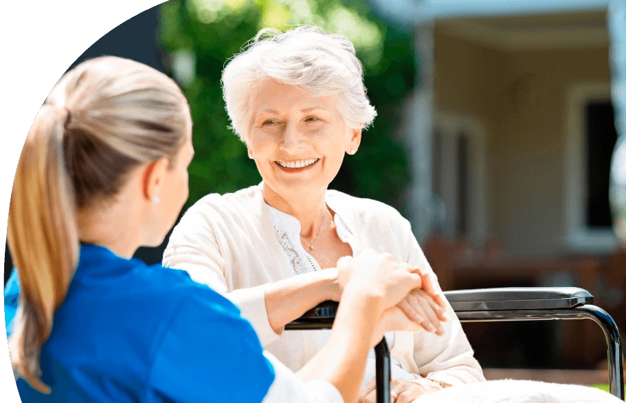 Eine Frau mit langen blonden Haaren und auffällig grünem Hemd steht mit dem Rücken zur Kamera und hält vor einer Gruppe junger Erwachsener einen Vortrag. Die Teilnehmenden sitzen in einem hellen Raum mit großen Fenstern, tragen weiße T-Shirts und wirken aufmerksam und interessiert.