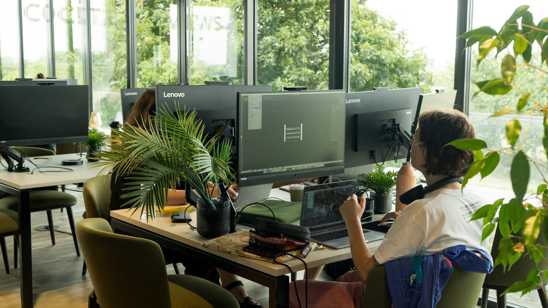 3 people working at partitioned desks in a coworking area