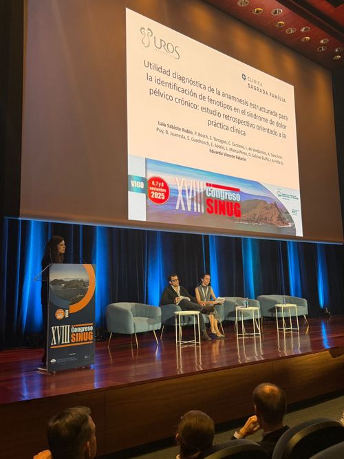 Escenario de conferencia con una ponente hablando desde el atril, junto a una pantalla grande que muestra una diapositiva en español titulada 'Por qué este estudio', durante el XVII Congreso SINUG.