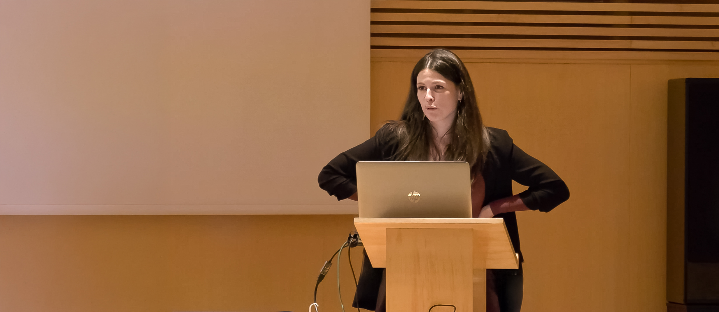 Dra. Laia Sabiote durante su ponencia en la Jornada UROS hablando sobre vejiga hiperactiva y urología funcional desde un atril con ordenador portátil.