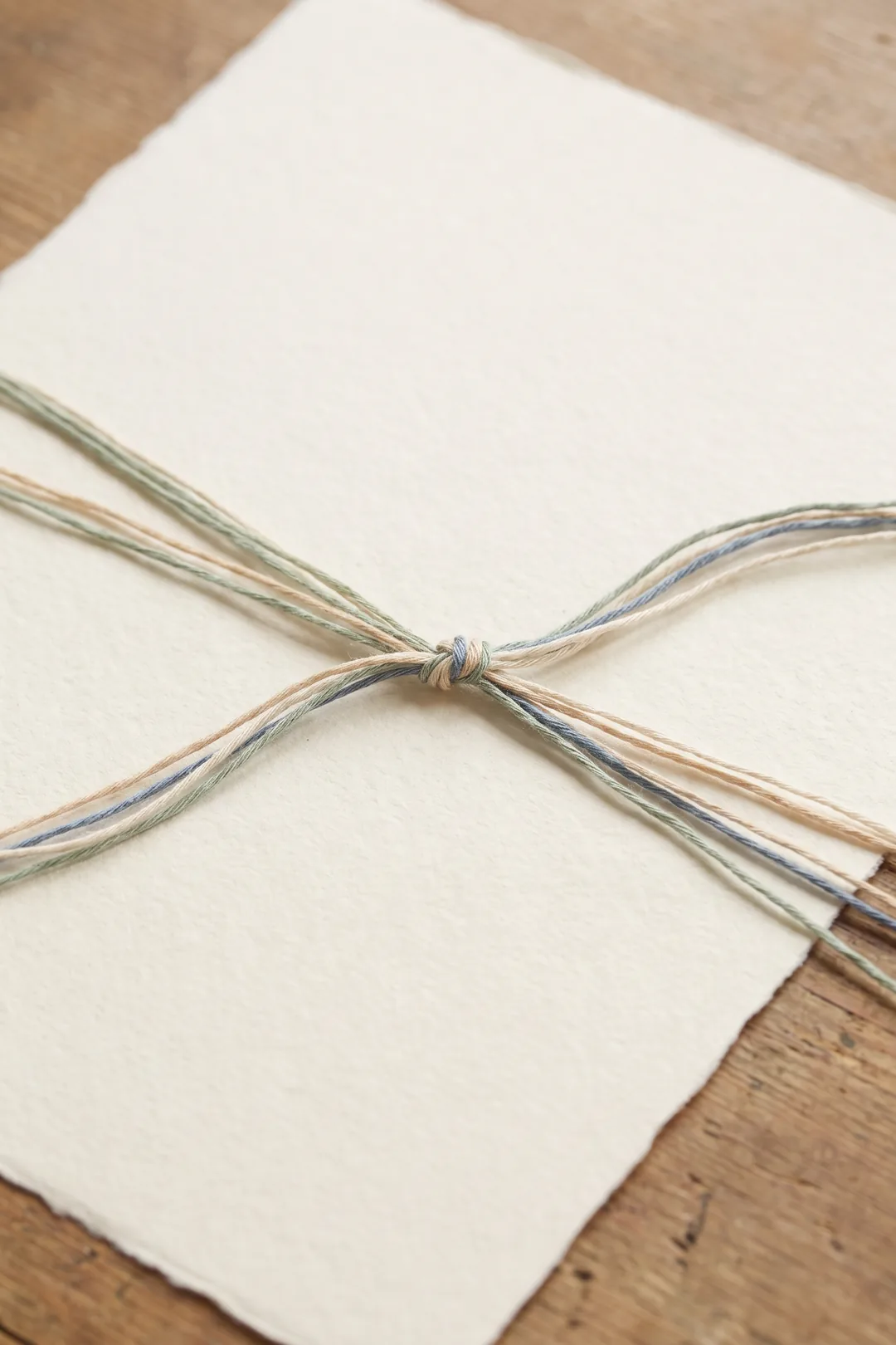 Imagen ilustrativa: hilos finos de tonos suaves que llegan desde distintos lados y convergen en un nudo sobre papel crema