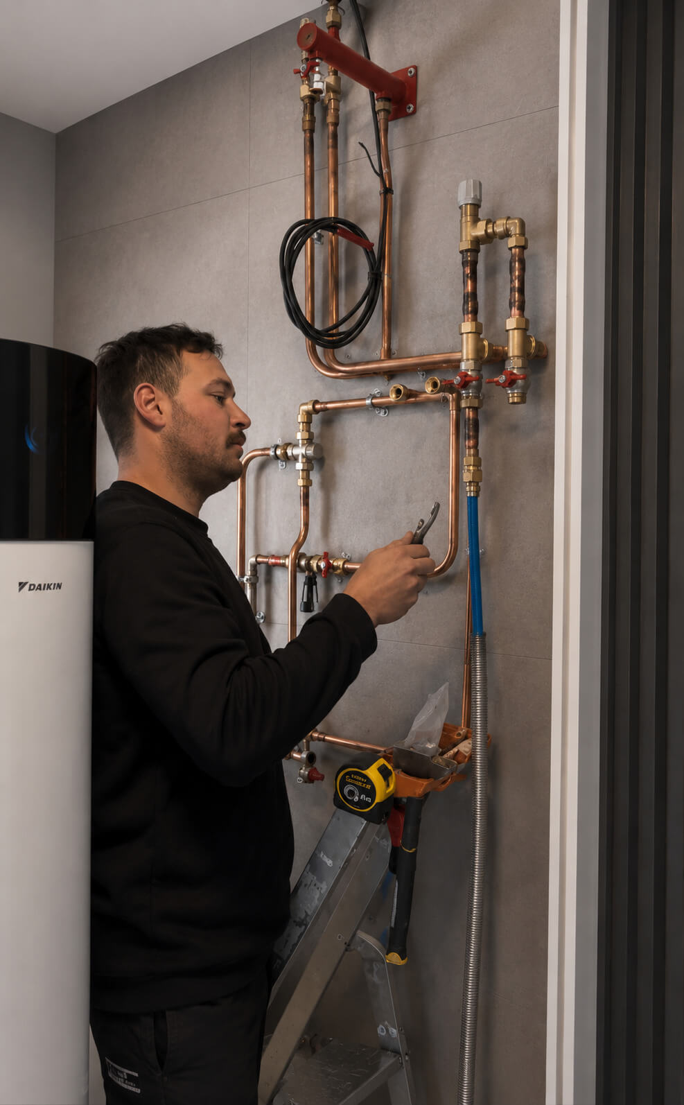 Technicien A+ Solaire travaillant sur les raccordements d’une pompe à chaleur dans une maison moderne.