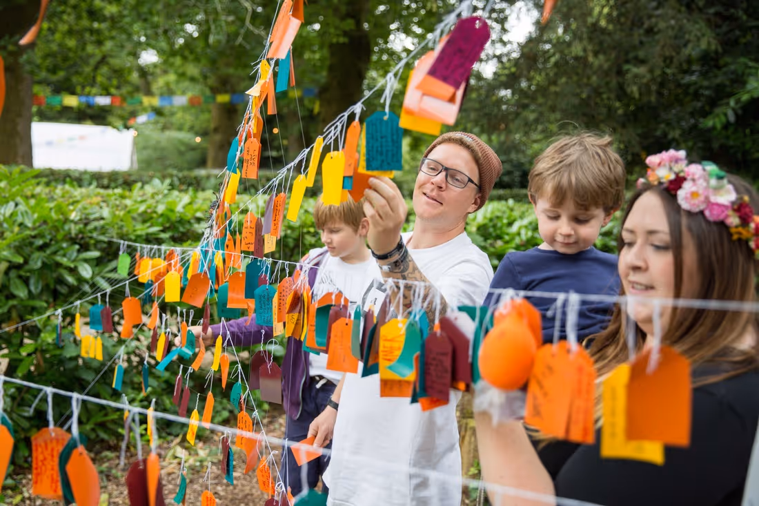 People engaging with installation made from hand written notes on luggage tags.